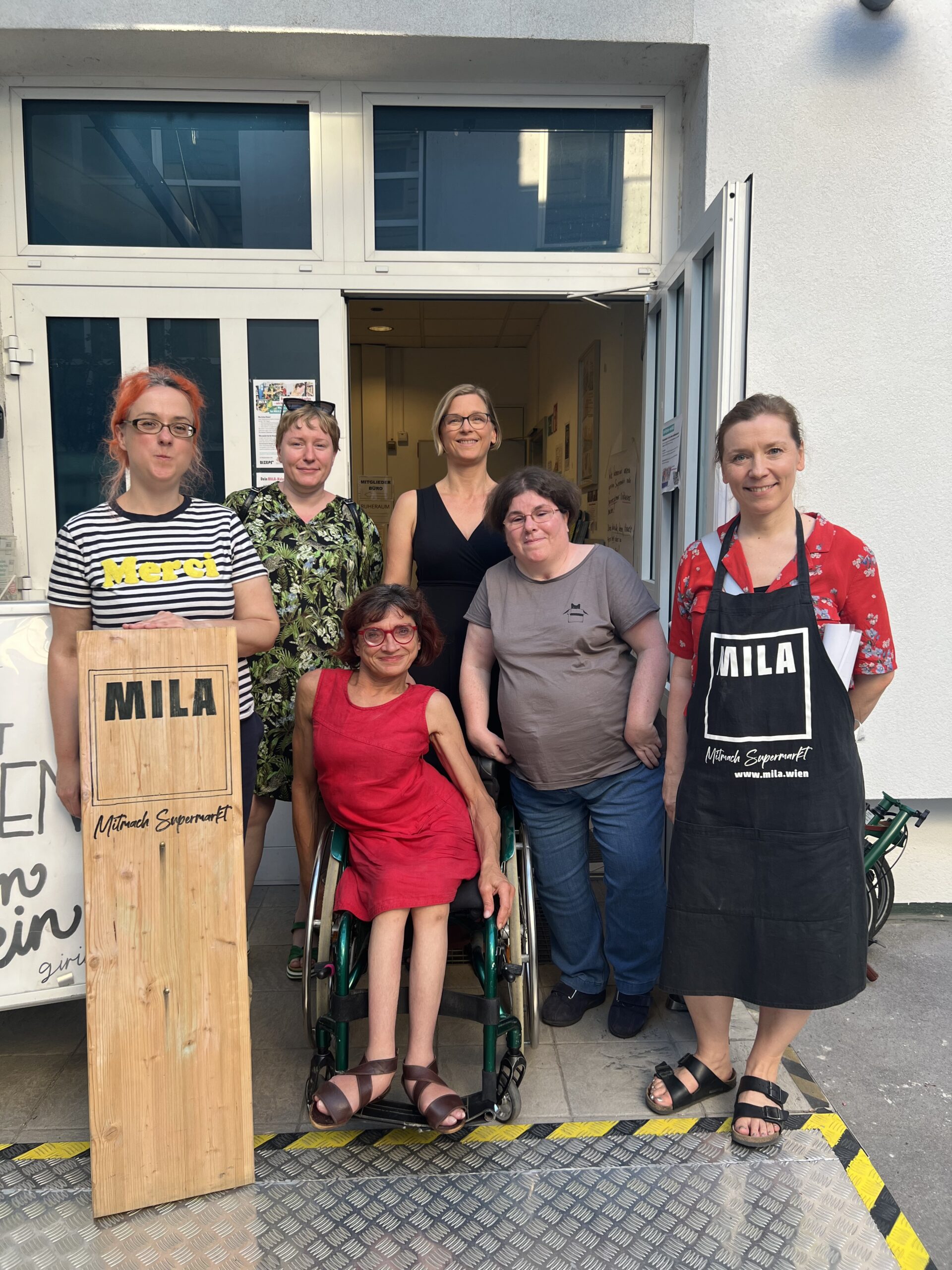 Gruppenfotos von Frauen vor MILA Supermarkt mit MILA-Schild